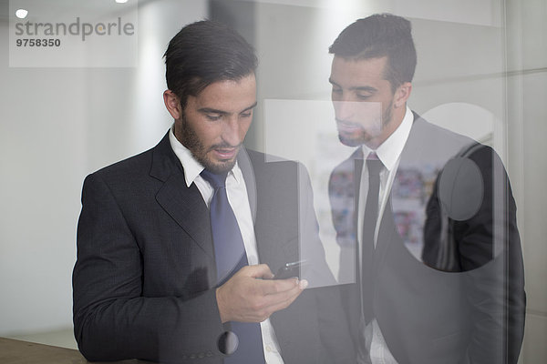 Zwei Geschäftsleute im Büro mit Blick auf das Handy