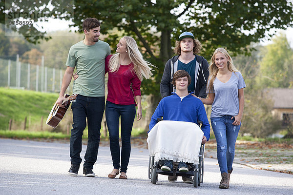 Junger Mann im Rollstuhl mit Freunden