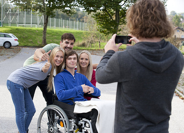 Junger Mann fotografiert seine Freunde mit dem Smartphone