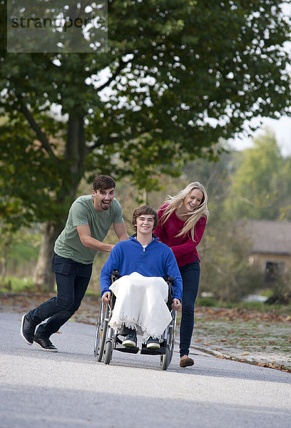 Junges Paar mit Freund im Rollstuhl sitzend