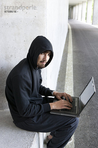 Portrait eines Hackers mit Laptop in der Tiefgarage