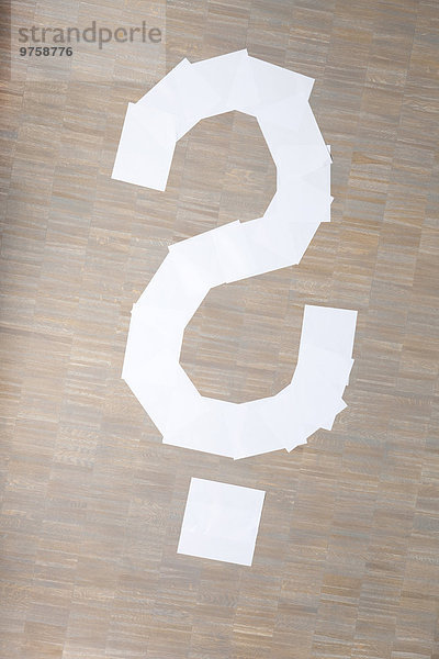Papierbögen in Form eines Fragezeichens auf dem Boden