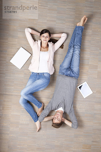 Mann und Frau auf dem Boden liegend mit Laptop und digitalem Tablett