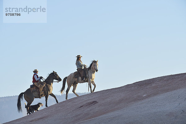 USA  Wyoming  zwei reitende Cowgirls und ihr Hund in Badlands