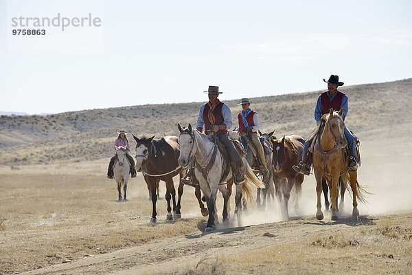 USA  Wyoming  Cowboys und Cowgirl führende Pferde in Badlands
