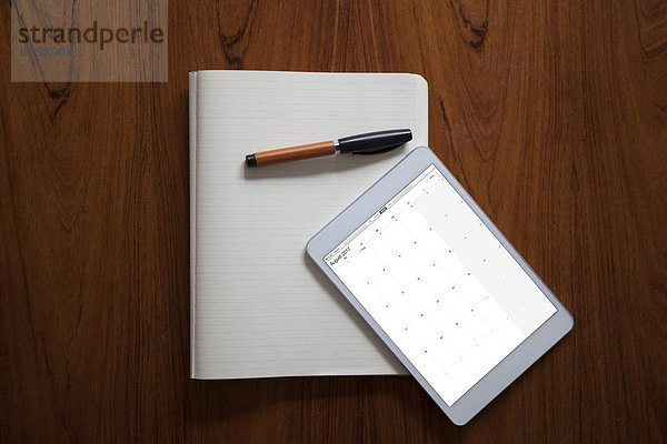 Digitales Tablett und Kugelschreiber auf geöffnetem Notebook liegend