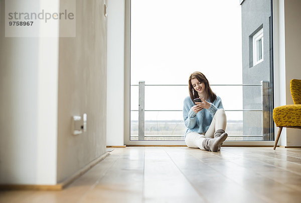 Junge Frau auf dem Boden sitzend mit digitalem Tablett
