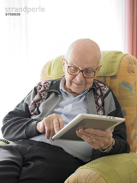 Alter Mann zu Hause mit digitalem Tablett