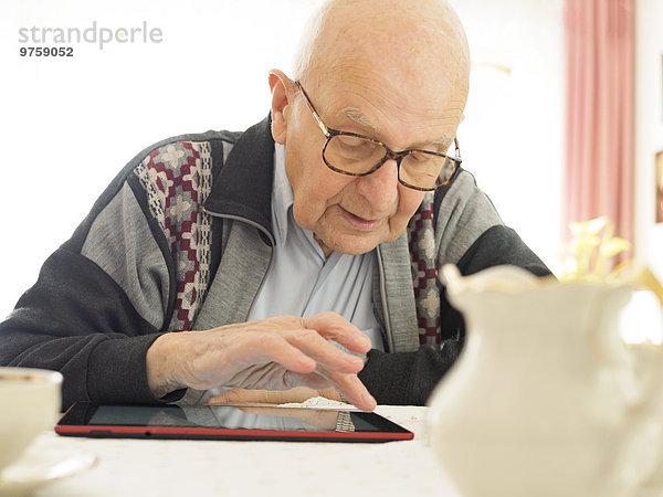 Alter Mann am Tisch sitzend mit digitalem Tablett