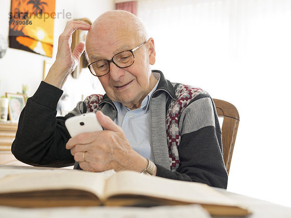 Alter Mann am Tisch sitzend mit dem Handy