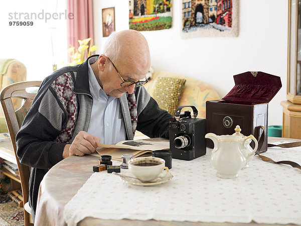 Alter Mann am Tisch sitzend mit alter Kamera
