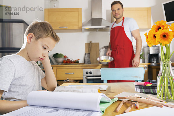 Junge sitzt am Küchentisch mit seinen Hausaufgaben
