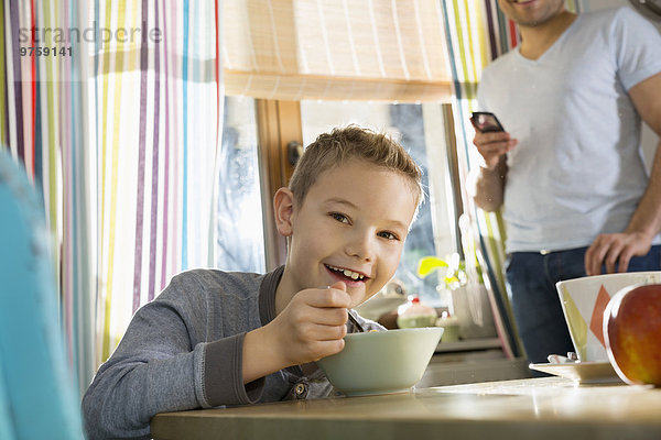 Porträt eines lächelnden Jungen am Frühstückstisch mit Granola