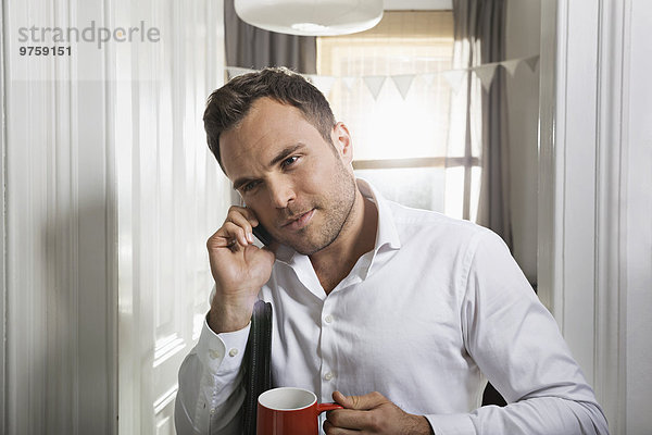 Portrait eines Geschäftsmannes mit Tasse Kaffee telefonieren zu Hause