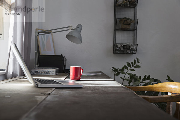 Schreibtisch mit Laptop und Kaffeetasse im Home Office