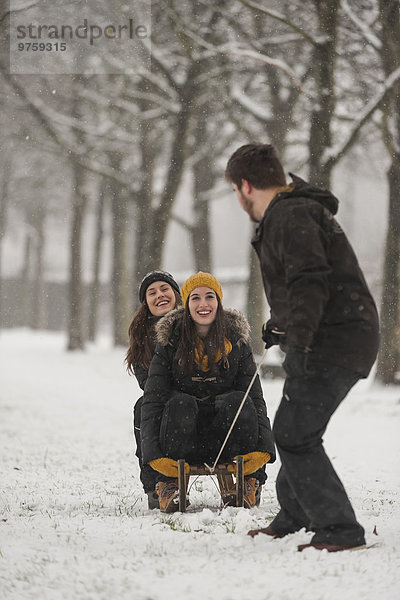 Drei Freunde beim Schlittenfahren im Winter