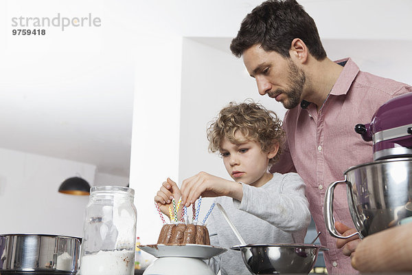 Vater und Sohn bereiten Geburtstagskuchen in der Küche vor