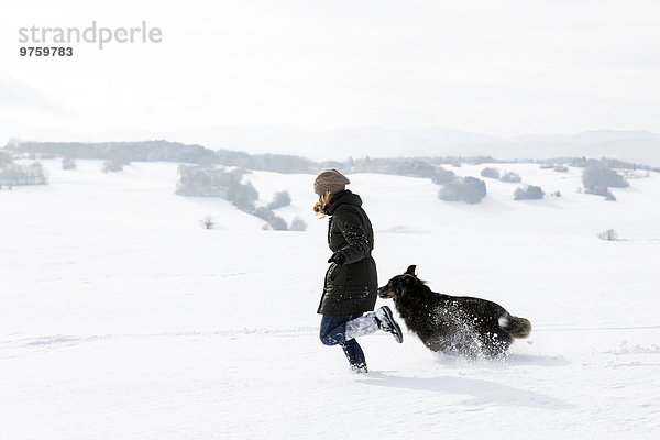 Deutschland  Baden-Württemberg  Waldshut-Tiengen  Frau und Hund im Schnee laufend