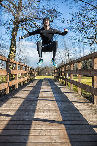 Spanien  Gijon  Sportler beim Springen auf Holzbrücke