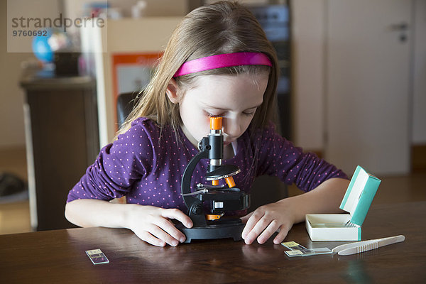 Kleines Mädchen mit Mikroskop zu Hause