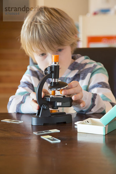 Junge mit Mikroskop zu Hause