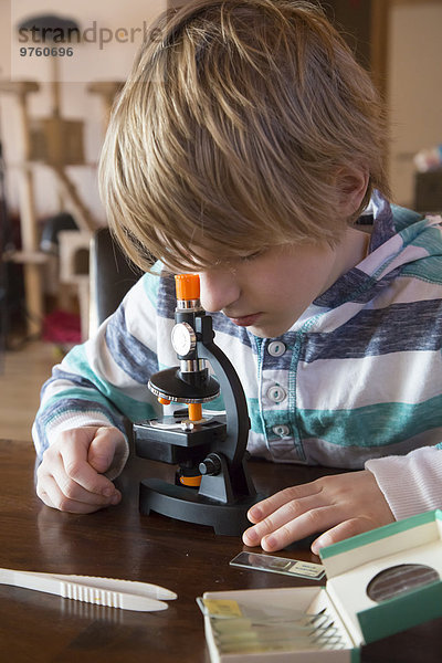 Junge mit Mikroskop zu Hause