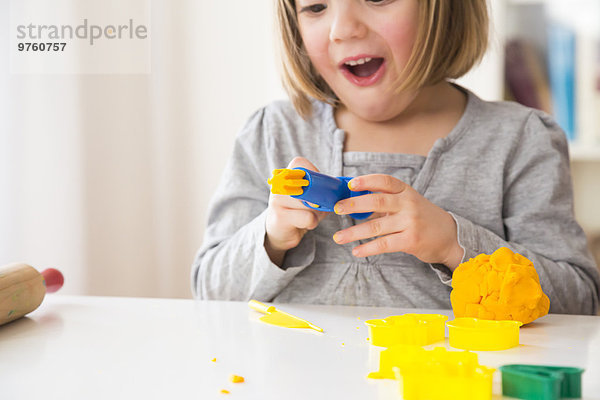Kleines Mädchen spielt mit gelber Knetmasse