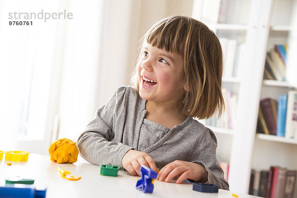 Kleines Mädchen spielt mit gelber Knetmasse