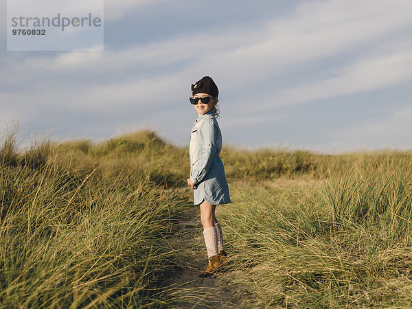Spanien  Ferrol  kleines Mädchen mit übergroßer Sonnenbrille in Stranddünen stehend