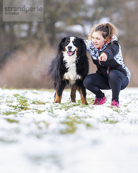 Deutschland  junge Frau mit ihrem Bernhardiner auf verschneiter Wiese