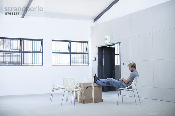 Kreativer Büromensch entspannt auf Stuhl und Boxen
