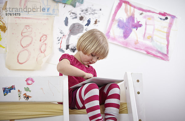 Kleines Mädchen auf Etagenbett sitzend  Zeichnung auf Touchpad