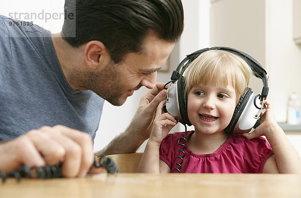 Vater und Tochter hören Musik über Kopfhörer