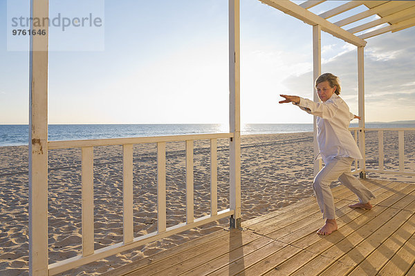 Portugal  Algarve  Frau beim Yoga am Strandhaus bei Sonnenuntergang