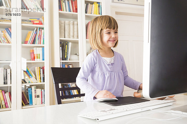 Lächelndes kleines Mädchen  das Zeit am Computer verbringt.