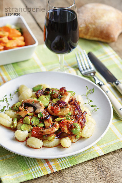 Fava-Bohnen und Champignons auf Gnocchi  serviert mit Salat  Rotwein und Brot