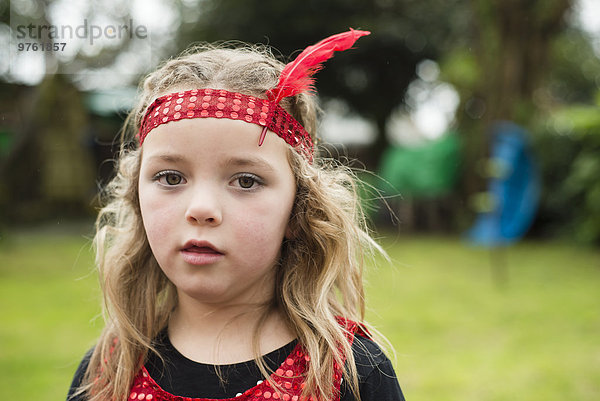 Porträt des kleinen Mädchens mit rotem Haarreif und Feder