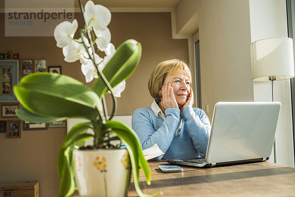 Seniorin zu Hause mit Laptop-Denken