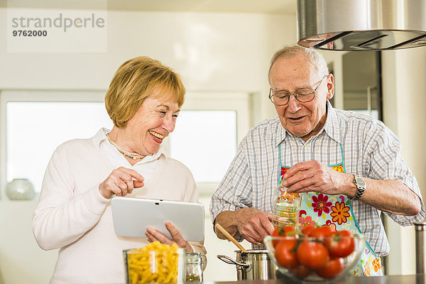 Seniorenpaar mit digitalem Tablettenkochen in der Küche