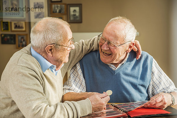 Zwei glückliche Seniorenfreunde mit Münzalbum