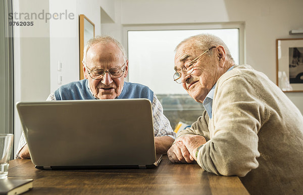 Zwei ältere Freunde beim Blick auf den Laptop