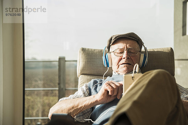 Senior Mann zu Hause entspannt mit Kopfhörer