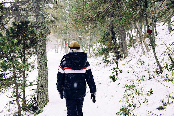 Junge  der im Winter durch den Wald läuft.