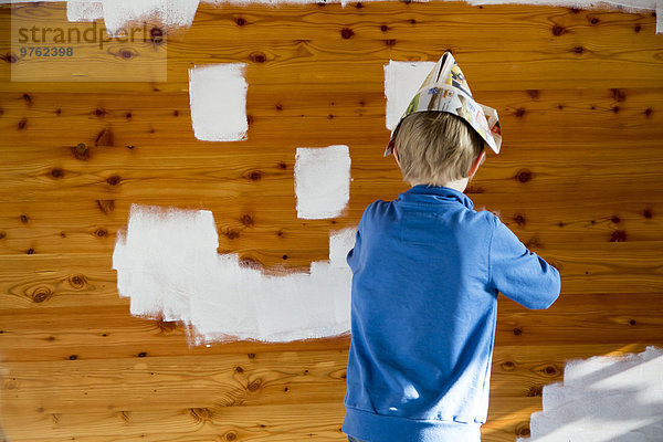 Junge malt Smiley-Gesicht auf Holzwand
