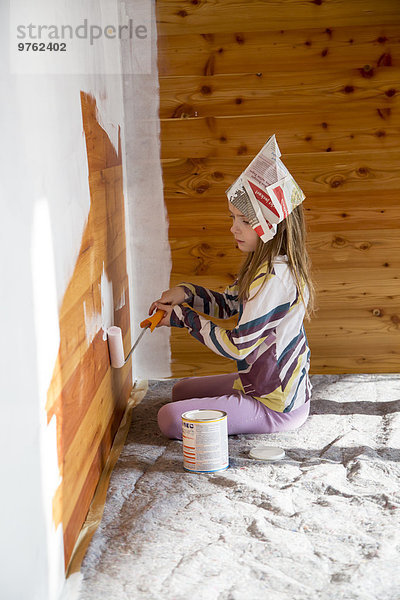 Mädchen malen Holzwand mit Farbroller