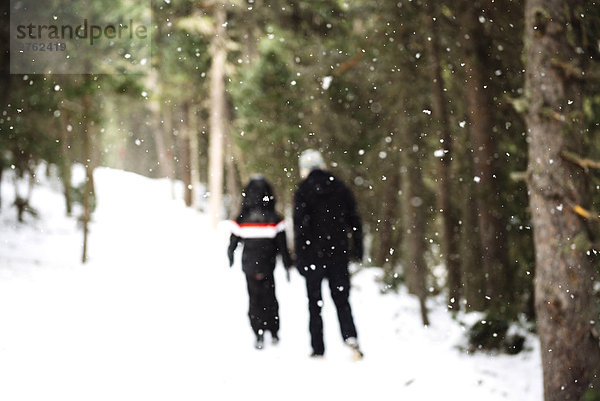 Mann und Kind beim Wandern durch den Wald im Schnee