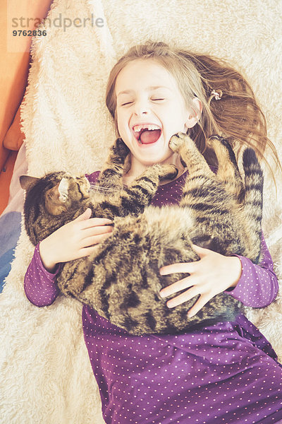 Glückliches Mädchen spielt mit Katze