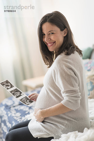 sitzend Frau lächeln halten Bett Schwangerschaft Ultraschalluntersuchung