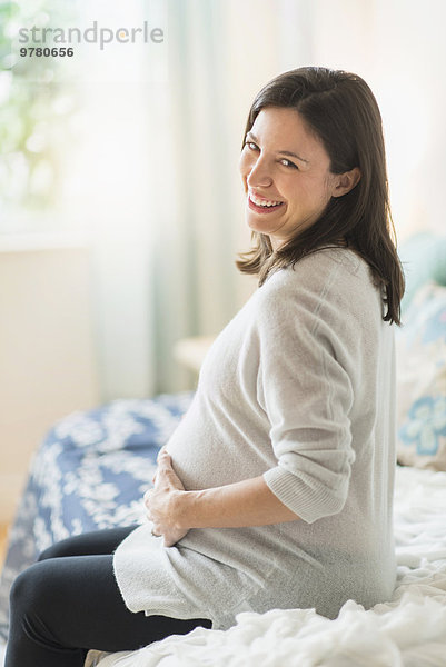 sitzend Frau lächeln halten Bett Schwangerschaft Ultraschalluntersuchung