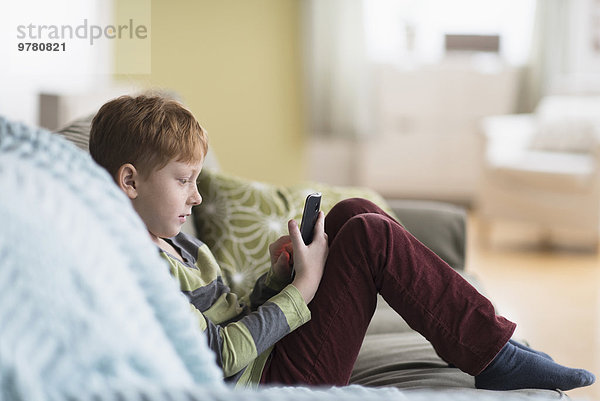 Handy sitzend benutzen Junge - Person Couch
